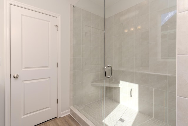 bathroom with wood-type flooring and an enclosed shower