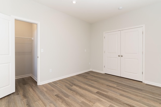 unfurnished bedroom with dark hardwood / wood-style flooring and a closet