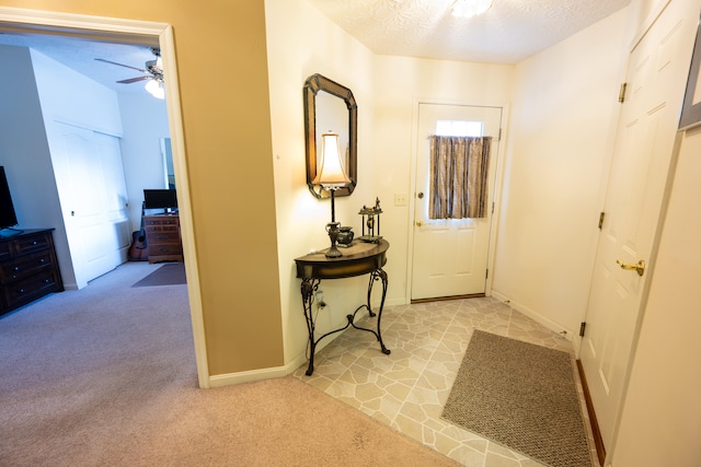 corridor featuring light colored carpet and a textured ceiling