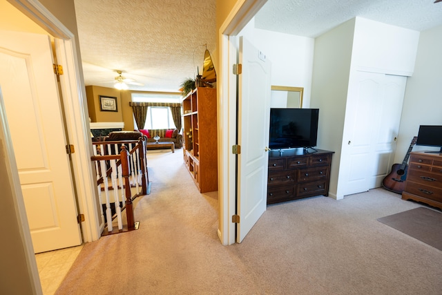 hallway featuring light colored carpet and a textured ceiling