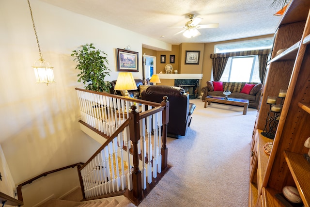 living room featuring ceiling fan, a fireplace, carpet floors, and a textured ceiling