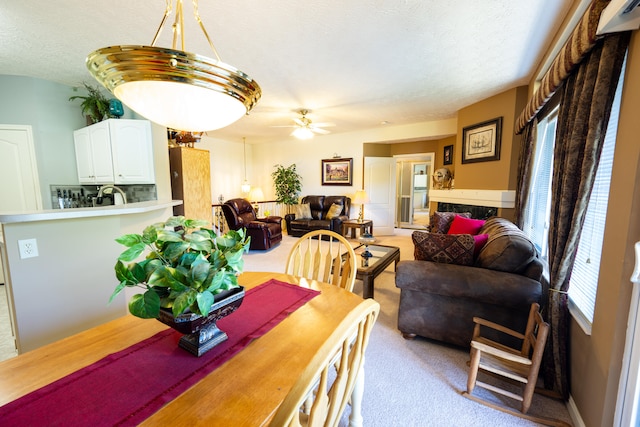 carpeted dining room featuring ceiling fan, a fireplace, and a textured ceiling