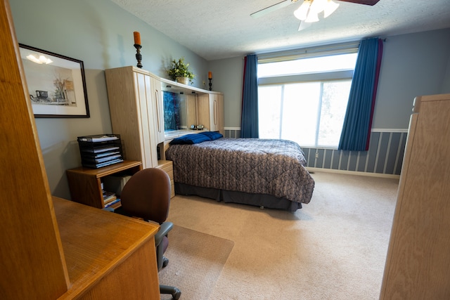 bedroom with ceiling fan, carpet floors, and a textured ceiling