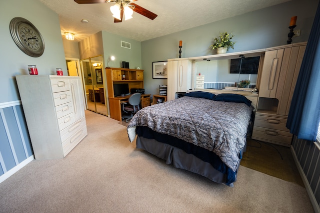 carpeted bedroom featuring ceiling fan, connected bathroom, a closet, and a textured ceiling