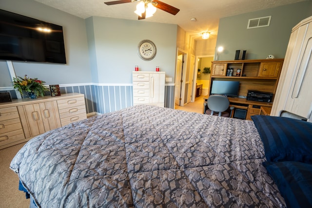 carpeted bedroom with ceiling fan, built in desk, and a textured ceiling