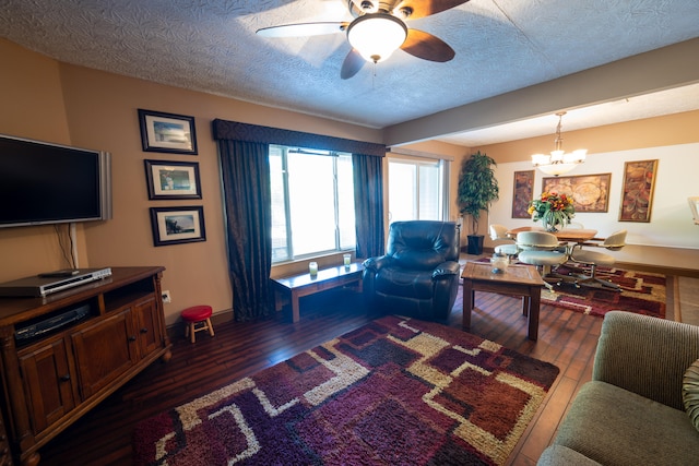 living room with dark hardwood / wood-style flooring, ceiling fan with notable chandelier, and a textured ceiling