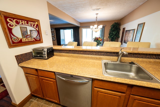 kitchen with dishwasher, sink, hanging light fixtures, a notable chandelier, and a textured ceiling