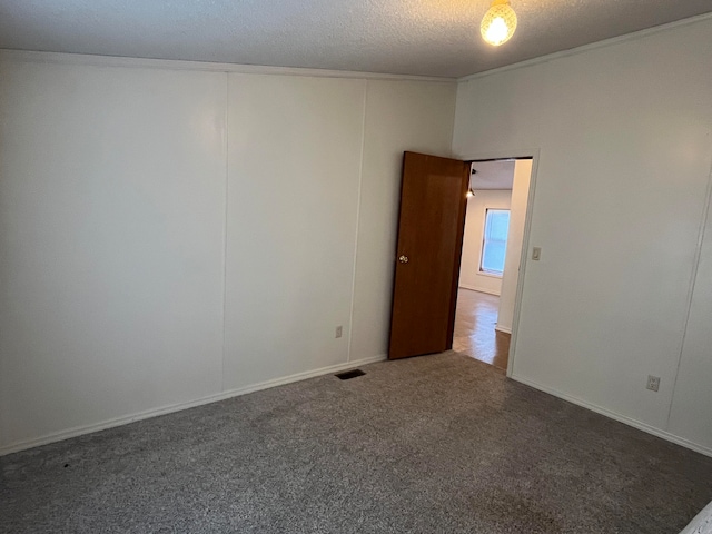 spare room with dark carpet and a textured ceiling