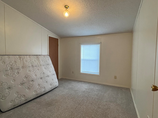 unfurnished bedroom featuring light colored carpet, a textured ceiling, and lofted ceiling