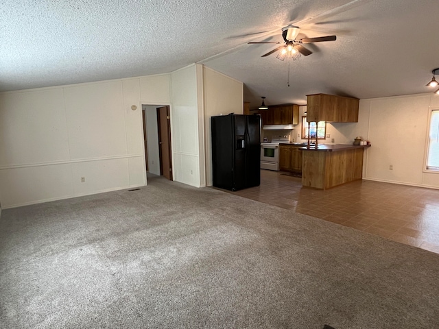 kitchen featuring a textured ceiling, black fridge, kitchen peninsula, stainless steel electric range, and ceiling fan