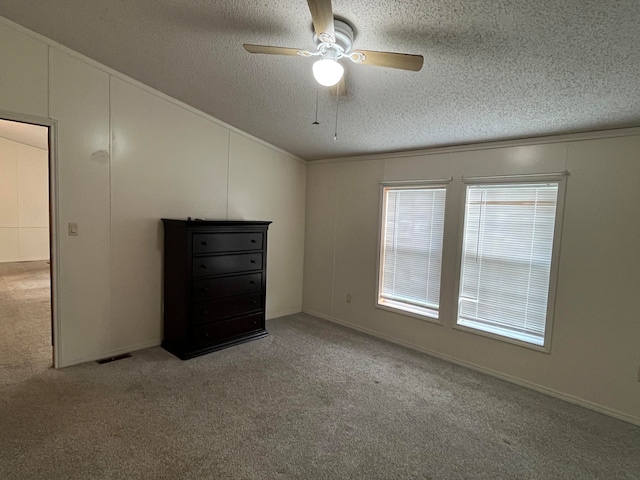 unfurnished bedroom with ceiling fan, light colored carpet, and a textured ceiling