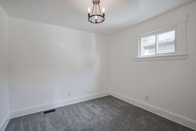 empty room featuring an inviting chandelier and dark colored carpet