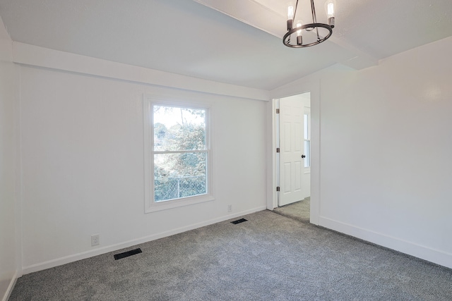 empty room featuring a notable chandelier, lofted ceiling, and carpet