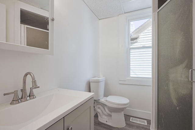 bathroom with wood-type flooring, vanity, toilet, and an enclosed shower