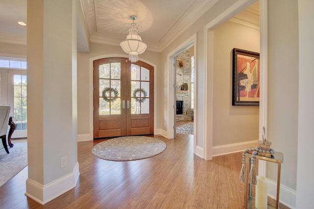 entryway with hardwood / wood-style floors, an inviting chandelier, ornamental molding, and french doors