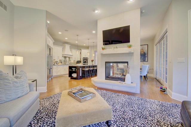 living room featuring a tile fireplace and light wood-type flooring