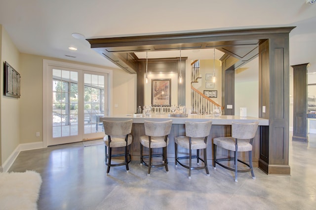 kitchen with a breakfast bar, hanging light fixtures, and concrete flooring