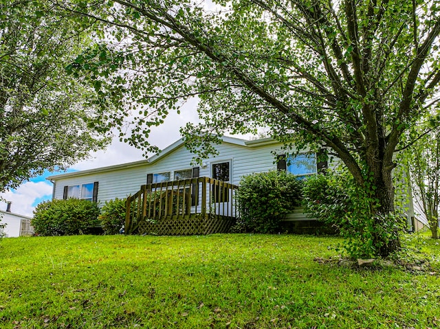 rear view of property featuring a lawn and a deck