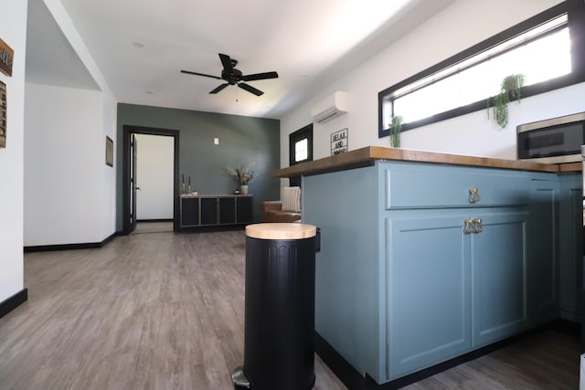 kitchen featuring blue cabinets, an AC wall unit, ceiling fan, and hardwood / wood-style flooring