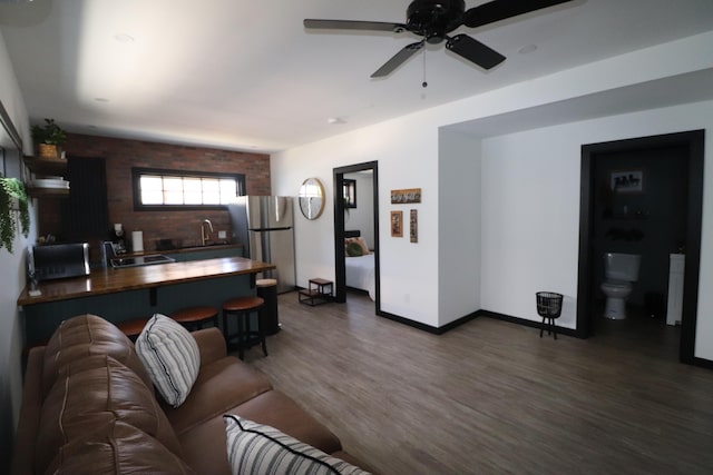 living room with ceiling fan, sink, and dark wood-type flooring