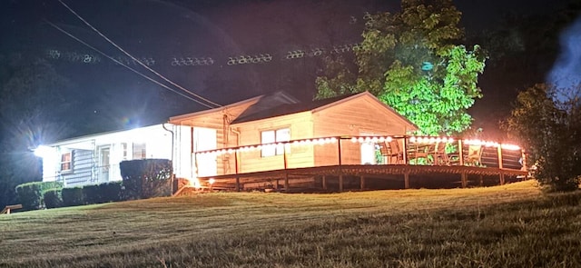 back house at twilight with a yard and a deck