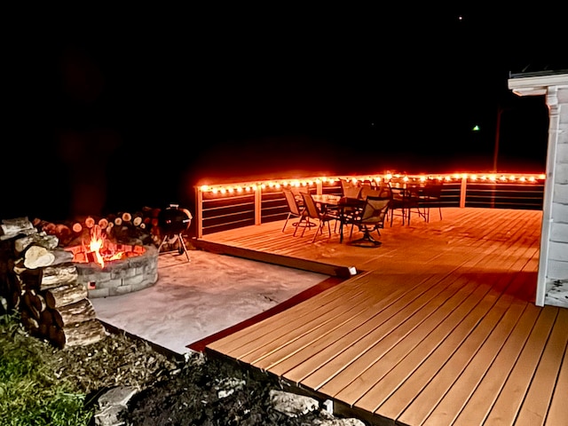 patio at night featuring a wooden deck and an outdoor fire pit