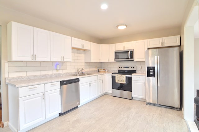 kitchen featuring appliances with stainless steel finishes, backsplash, white cabinetry, and sink