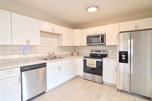 kitchen featuring stainless steel appliances, backsplash, sink, and white cabinetry