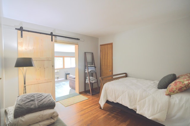 bedroom with hardwood / wood-style flooring and a barn door