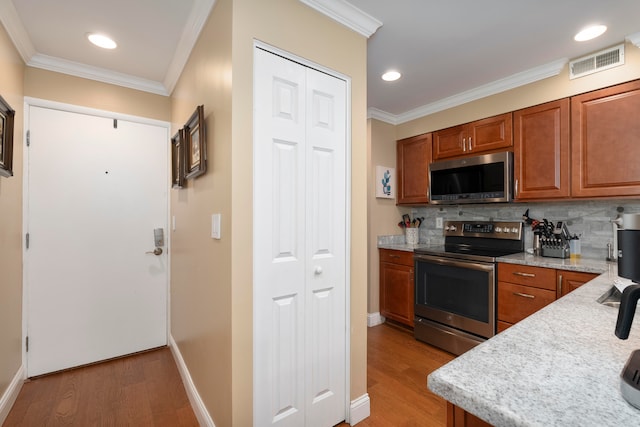 kitchen with ornamental molding, appliances with stainless steel finishes, backsplash, and light hardwood / wood-style floors