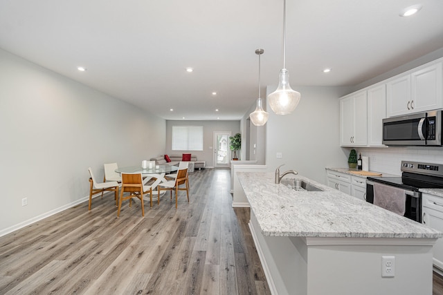 kitchen with stainless steel appliances, hanging light fixtures, sink, and white cabinetry