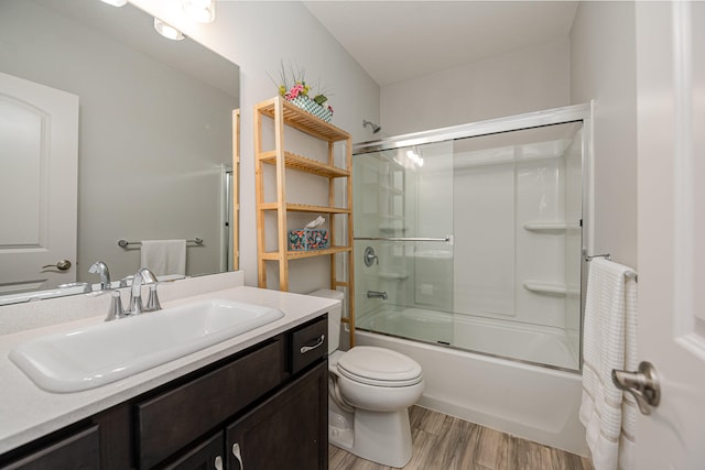 full bathroom with hardwood / wood-style floors, combined bath / shower with glass door, vanity, and toilet