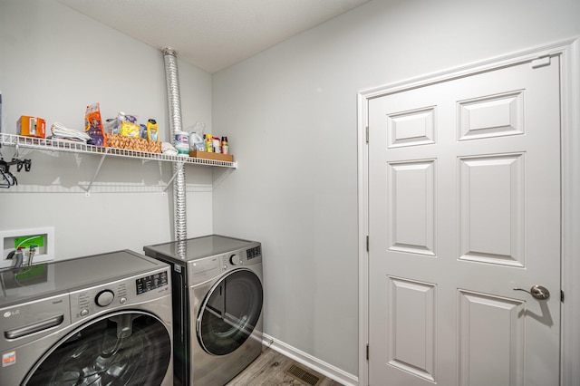 clothes washing area with wood-type flooring and washer and dryer