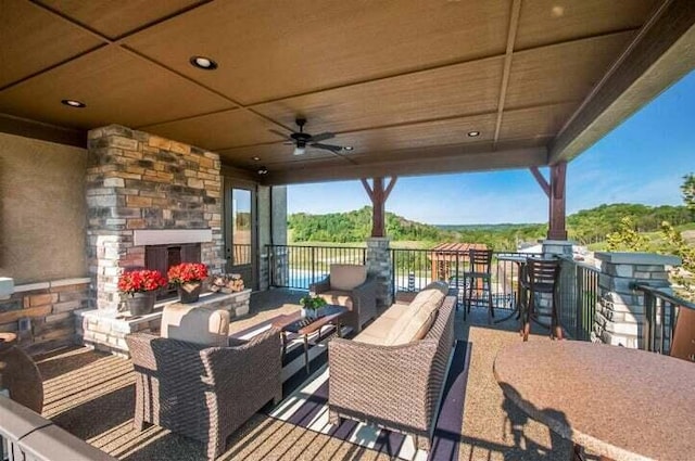 view of patio with an outdoor living space with a fireplace and ceiling fan