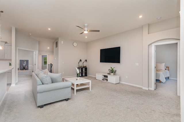 living room featuring vaulted ceiling, ceiling fan, and light colored carpet