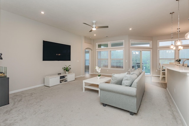 carpeted living room featuring ceiling fan with notable chandelier