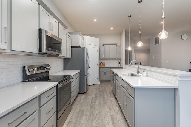 kitchen with stainless steel appliances, hanging light fixtures, sink, and tasteful backsplash