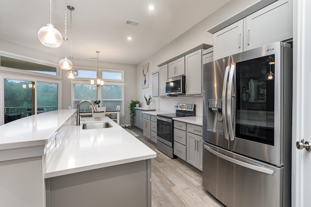 kitchen with gray cabinets, stainless steel appliances, hanging light fixtures, and sink