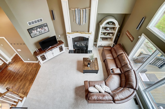 living room with a fireplace, a towering ceiling, and wood-type flooring