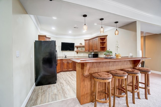 kitchen featuring a kitchen breakfast bar, pendant lighting, light hardwood / wood-style floors, black appliances, and ornamental molding