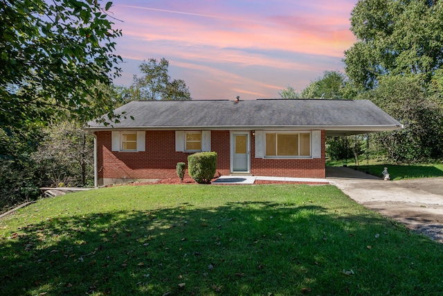 ranch-style home featuring a lawn and a carport