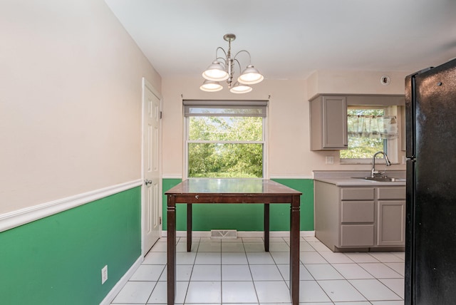 unfurnished dining area with light tile patterned flooring, a chandelier, and sink