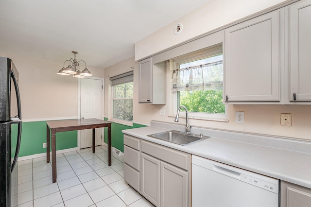 kitchen with pendant lighting, sink, dishwasher, an inviting chandelier, and black refrigerator