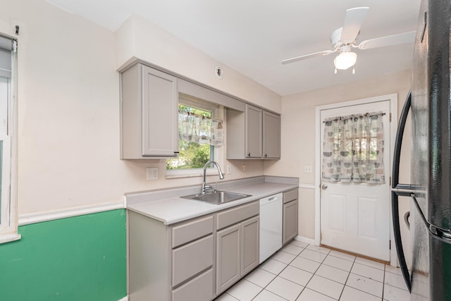 kitchen featuring gray cabinets, dishwasher, sink, light tile patterned floors, and stainless steel fridge