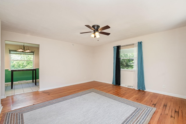 empty room featuring light hardwood / wood-style flooring and ceiling fan with notable chandelier