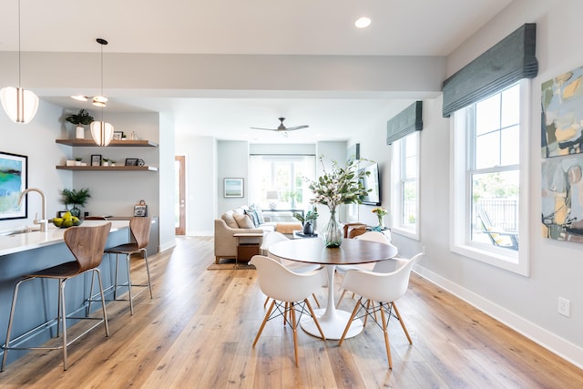 dining space featuring light wood-type flooring, sink, and ceiling fan