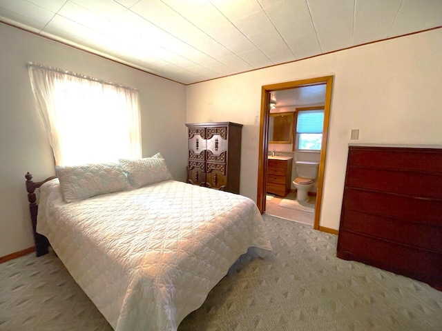 carpeted bedroom with ensuite bath and multiple windows