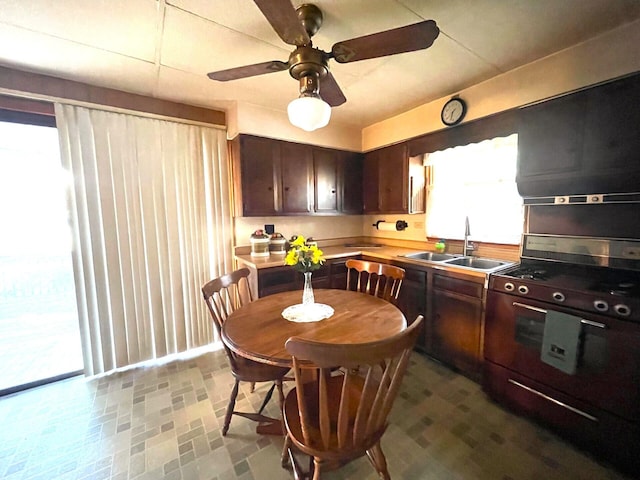 kitchen featuring dark brown cabinets, gas stove, ceiling fan, and sink