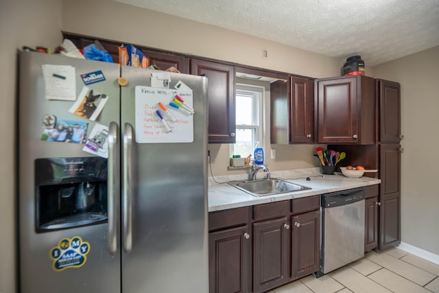 kitchen featuring appliances with stainless steel finishes, sink, a textured ceiling, dark brown cabinetry, and light tile patterned floors