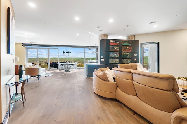 living room with expansive windows, light wood-type flooring, and plenty of natural light